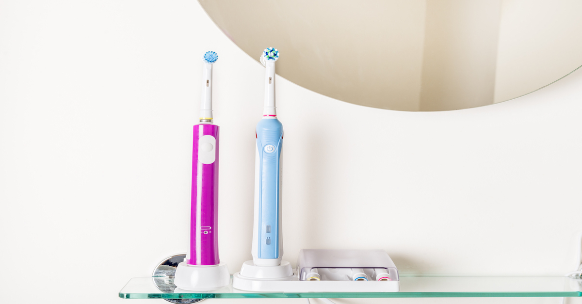 cepillos dentales eléctricos en repisa de cristal